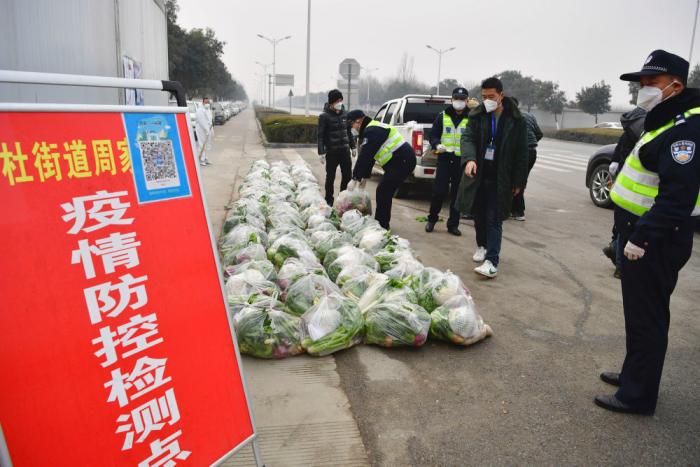 1月5日，民警在西安市长安区郭杜街道周家庄村外搬运配送给居民的蔬菜。新华社记者 邵瑞 摄