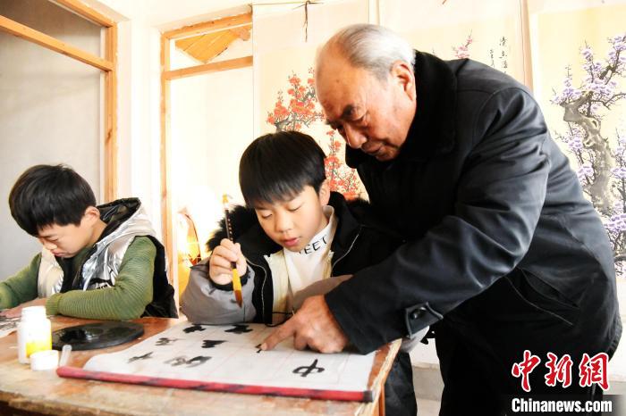 图为王魁士在辅导孩子们学习书法。　程学虎 摄