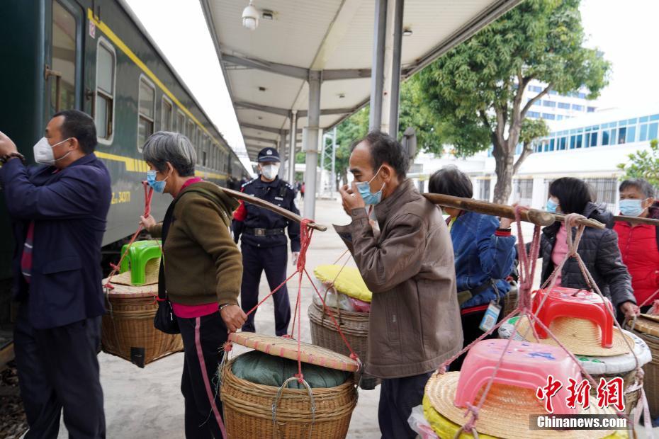 图为在广东廉江市河唇火车站，乘警引导“担担军”有序乘车。 中新社发 陈欣 摄