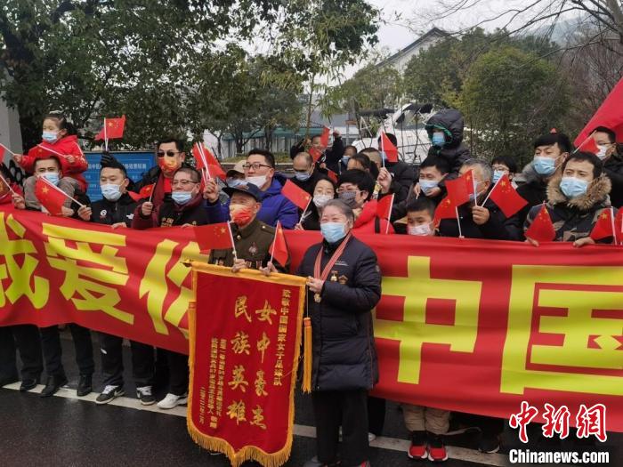 一位参加过抗美援朝的老兵举着一面写有“女中豪杰民族英雄”的锦旗。　高达 摄