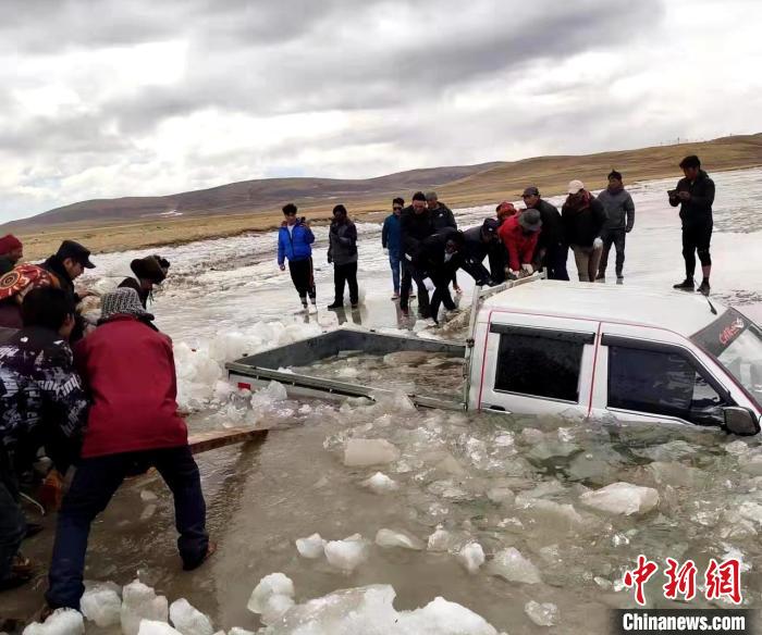 图为民警和牧民们一同将被困车辆成功拖出冰面。　玛多县委宣传部 供图