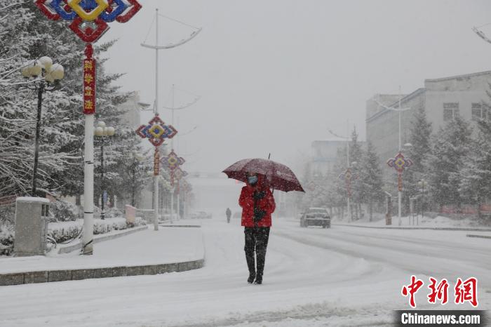 行人打伞在雪中行走。　冯宏伟 摄