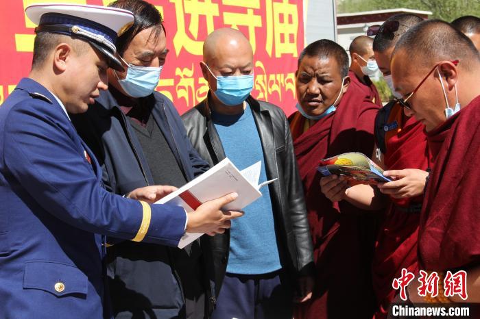 图为消防员向西藏佛学院领导以及僧尼学员宣传讲解消防知识手册。　西藏佛学院消防大队供图