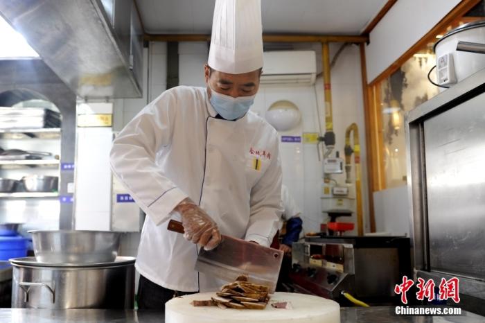 图为5月13日，陕西省级非遗项目“澄城水盆羊肉”代表性传承人王会斌切羊肉。 中新社发 高铖 摄