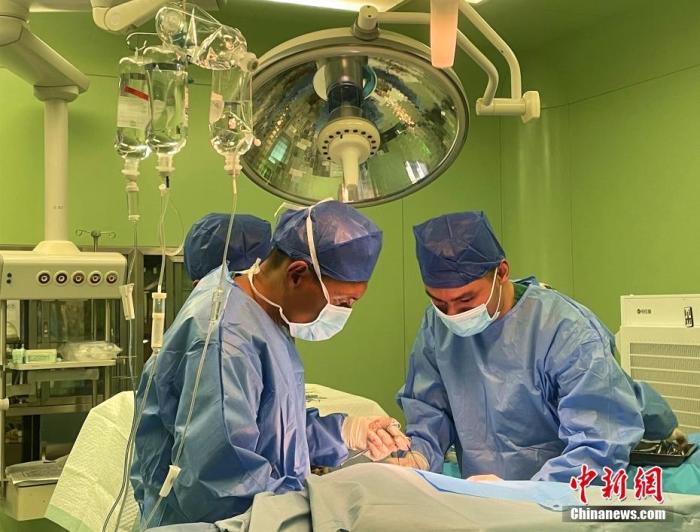 图为5月7日，次仁云丹(左)在拉萨为患者进行手术治疗。 中新社记者 冉文娟 摄