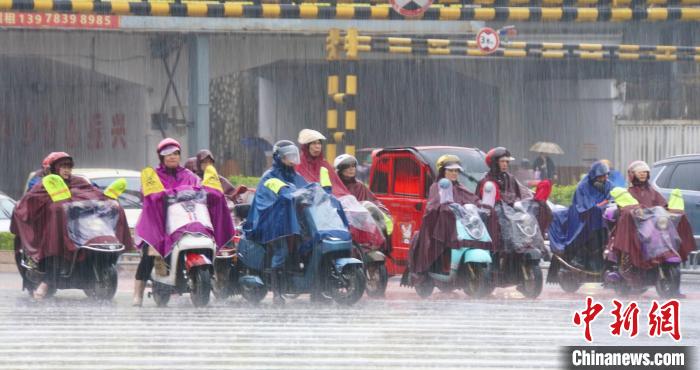 5月10日，桂林市民身披雨具在十字路口等待绿灯。　蒋丰慧？?　摄