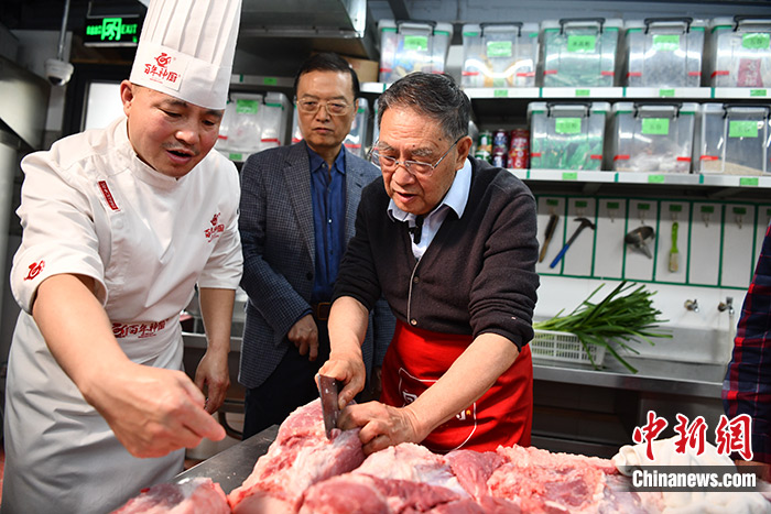 四川成都，在一家打着“三代人都爱吃的回锅肉”招牌的川菜店内，川菜大师王开发(右)正在准备炒回锅肉的二刀肉。中新社记者 张浪 摄