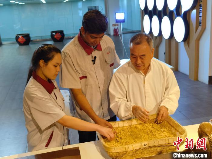 印度尼西亚在华留学生林精美(左一)和孟加拉国在华留学生谢民(中)在了解甜面酱制作流程中的制曲原理。　吕子豪 摄