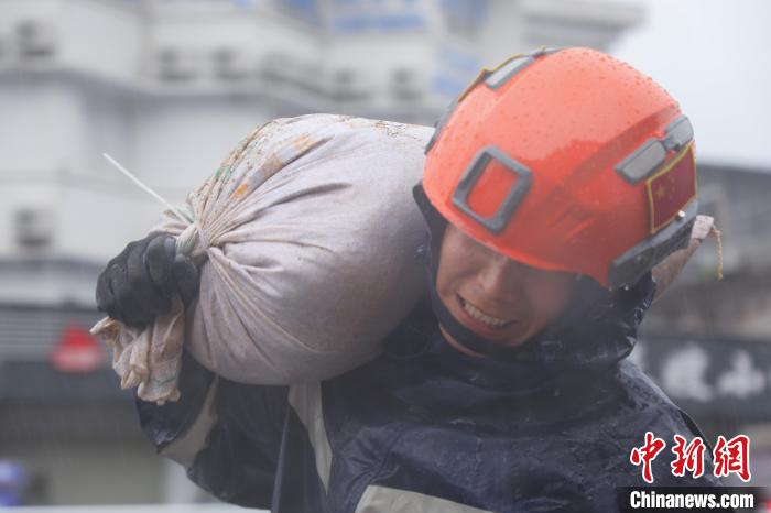 图为救援人员雨中搬运沙袋。　李袁辉 摄