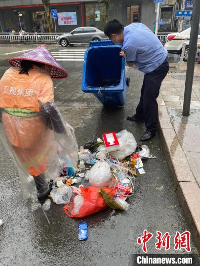 城关派出所民警冒雨在垃圾桶里翻找金珠子。　尤溪县公安局城关派出所供图