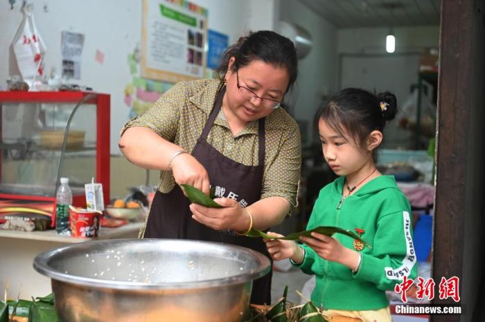 6月3日，是中国农历五月初五端午节。四川省雅安市宝兴县这座小城从地震中逐渐恢复元气，端午飘粽香，烟火气已归。图为宝兴县居民戴晓红教小朋友包粽子。 安源 摄