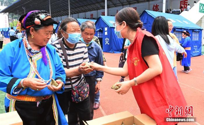 6月3日，是中国农历五月初五端午节。四川省雅安市宝兴县这座小城从地震中逐渐恢复元气，端午飘粽香，烟火气已归。图为志愿者在宝兴中学安置点里分发粽子。 安源 摄