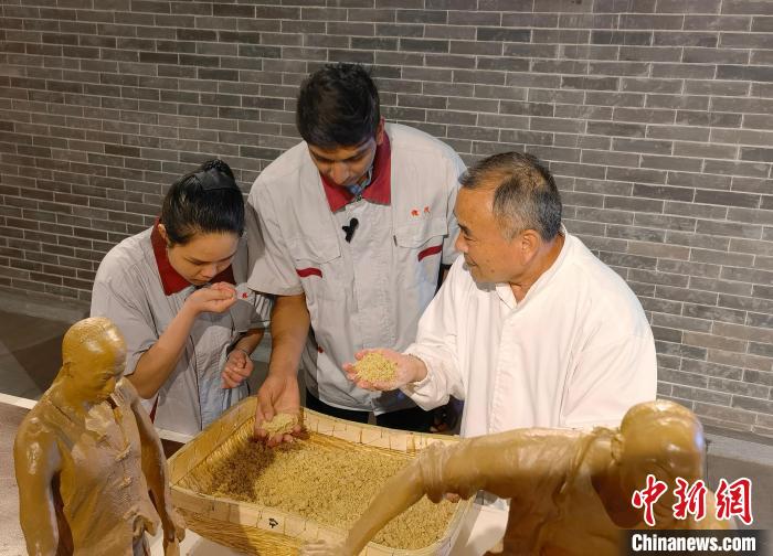 印度尼西亚在华留学生林精美(左一)和孟加拉国在华留学生谢民(中)在体验甜面酱制作流程之一——制曲。　吕子豪 摄