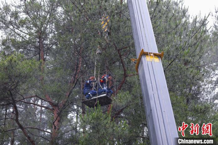 图为风雨中救援人员乘坐吊篮前往任务区域。　李袁辉 摄