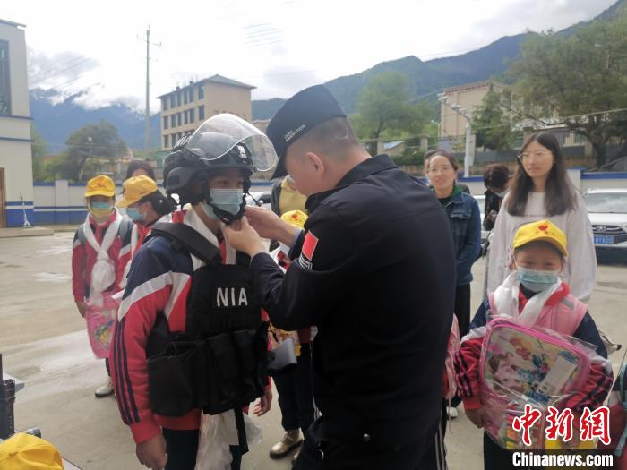 图为民警为小学生穿戴警用装备。　派边境派出所 摄