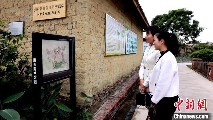 游客在河村观看露天画展。　玉林市宣传部供图