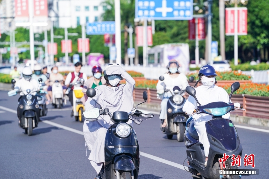 7月12日，广西南宁，市民“捂装”骑行。当日，南宁市气象台继续发布高温黄色预警信号。 中新社记者 陈冠言 摄