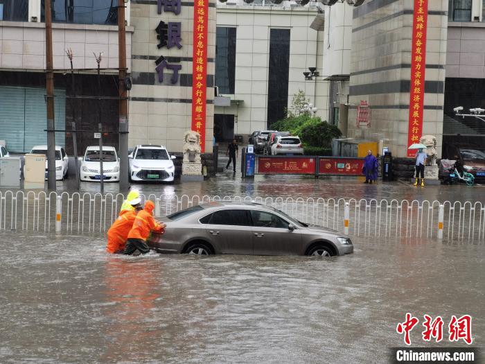 工作人员与交警一起，将抛锚车辆推离积水带。　太原城乡管理局供图