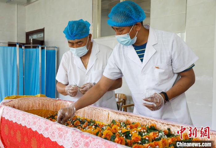 为逝者的棺椁铺上鲜花。　杨迪 摄