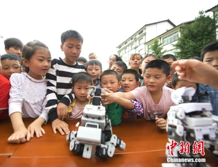 图为孩子们观察机器人。重庆科协供图