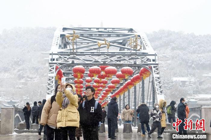 2月13日,甘肃兰州,游客在当地标志性建筑中山桥上自拍打卡。当日,兰州迎降雪天气。 九美旦增 摄 2月13日,甘肃兰州,游客在当地标志性建筑中山桥上自拍打卡。当日,兰州迎降雪天气。 九美旦增 摄