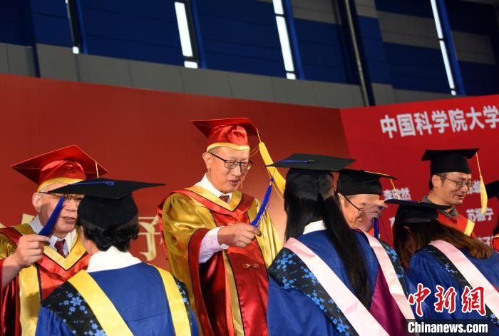 中科院副院长、国科大校长周琪院士为获得国科大学位学生代表扶正流苏。 中新社记者 孙自法 摄 中科院副院长、国科大校长周琪院士为获得国科大学位学生代表扶正流苏。 中新社记者 孙自法 摄