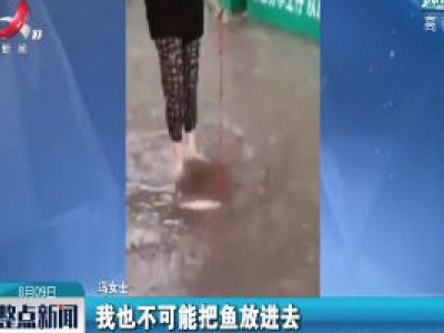 暴雨过后 她积水中“遛”鱼回家