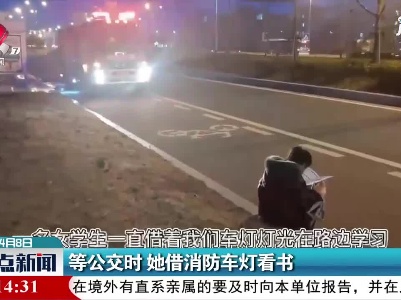 江苏淮安：等公交时 她借消防车灯看书